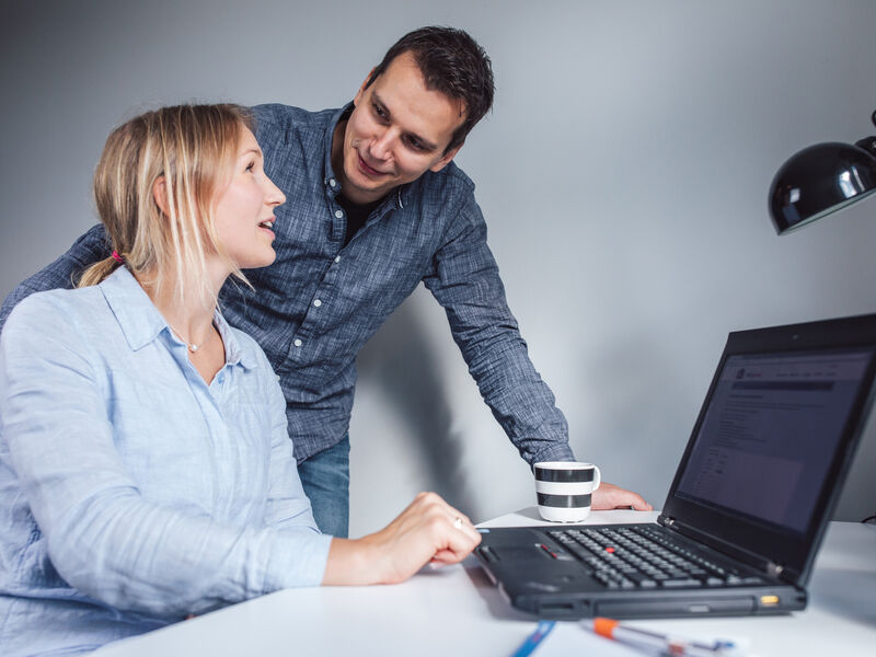 Mies ja nainen katselevat tietokonetta ja hymyilevät